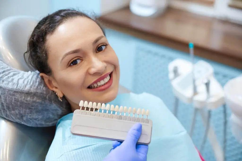 Patient comparing porcelain veneer shades with a dentist during a cosmetic dentistry consultation for a smile makeover.