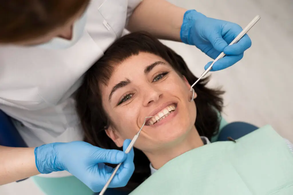 Smiling patient during a cosmetic dental consultation as a dentist examines teeth before a dental veneer procedure.