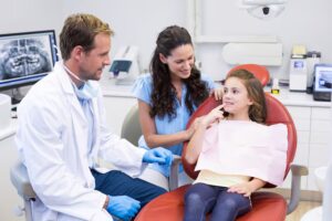 Child showing her teeth to a dentist during a pediatric dental examination.