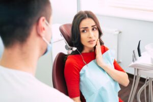 Woman experiencing tooth pain during a dental consultation with a dentist.